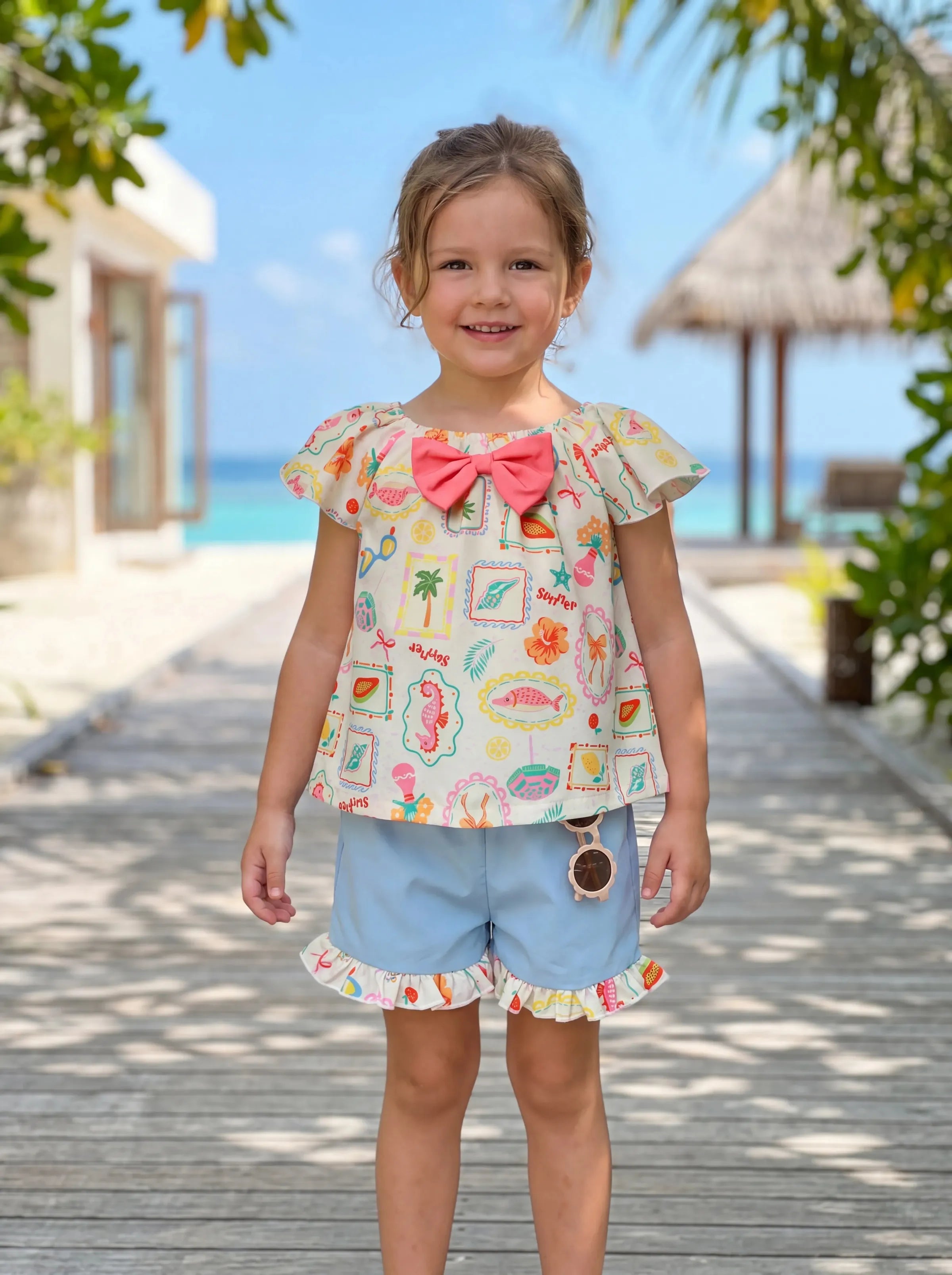 Toddler girl in a light pink ruffle flutter-sleeve tropical beach-print dress — coastal outfit for toddlers